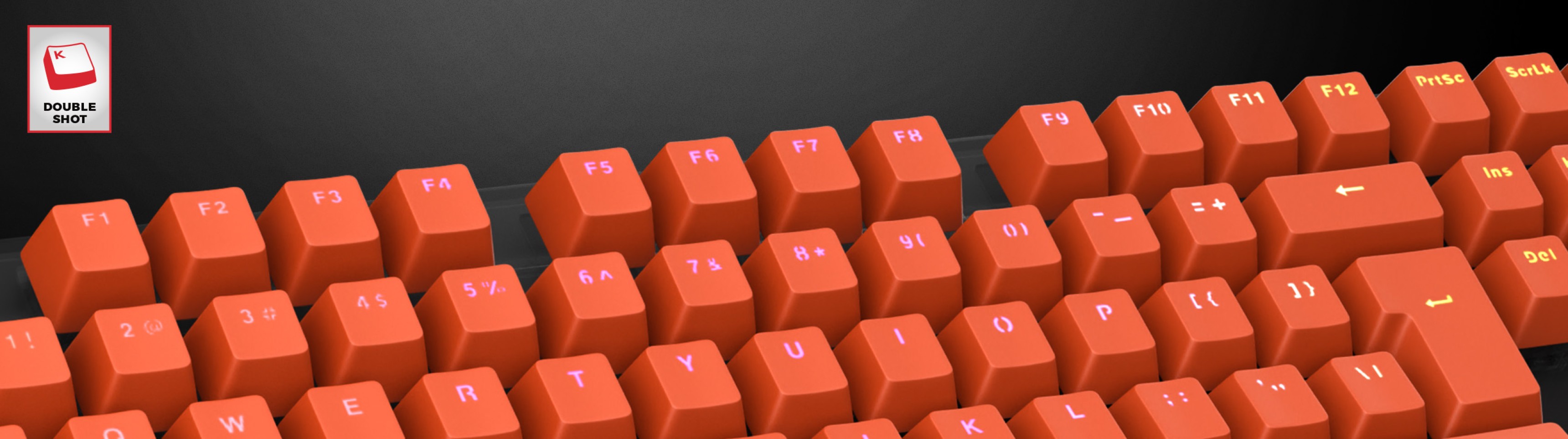 Claviers orange vif à double frappe disposés sur un clavier, comportant des lettres claires sur chaque touche.