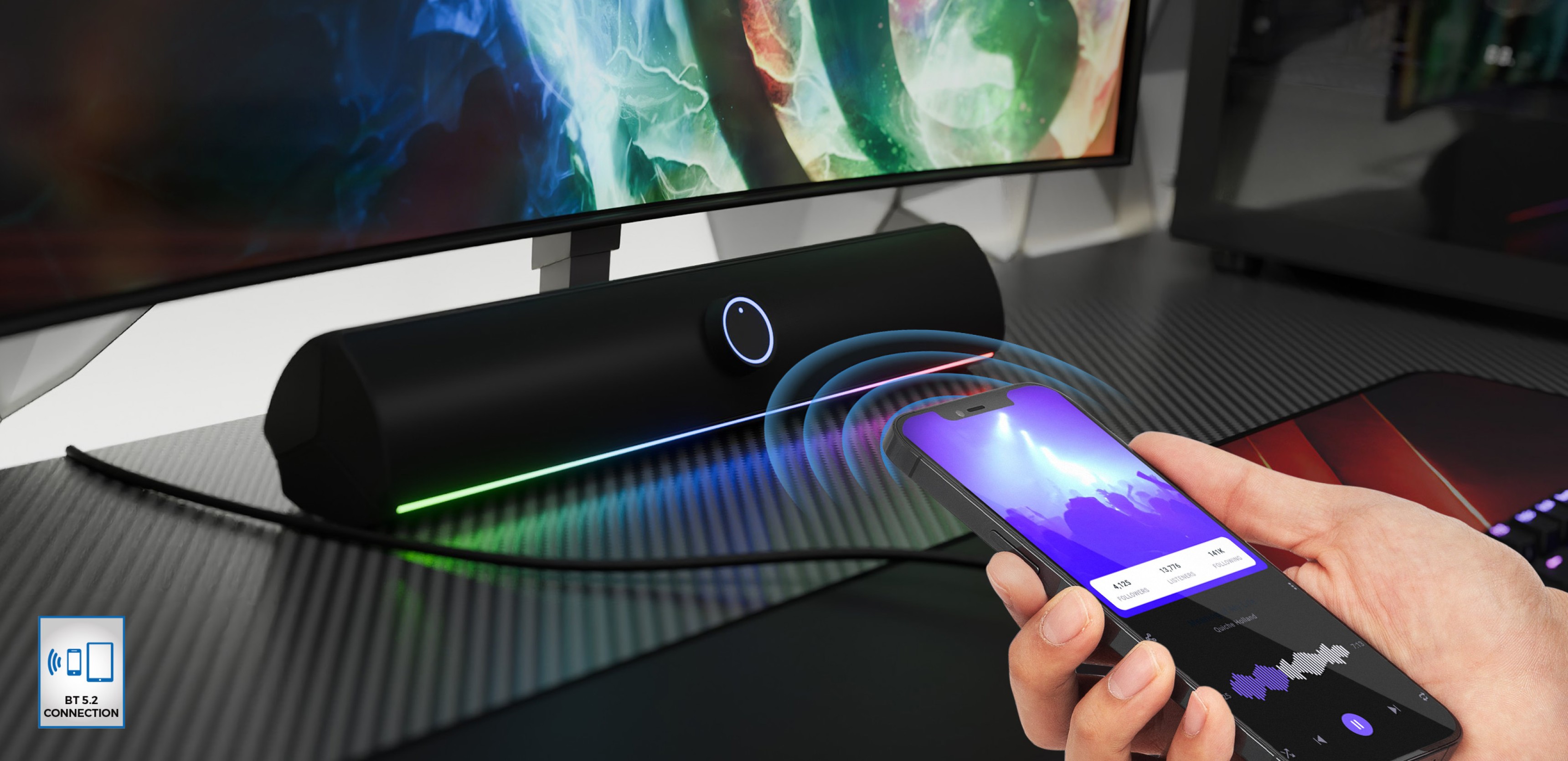 Barre de son Bluetooth noire avec éclairage LED, pouvant être commandée sans fil par un smartphone sur un bureau.