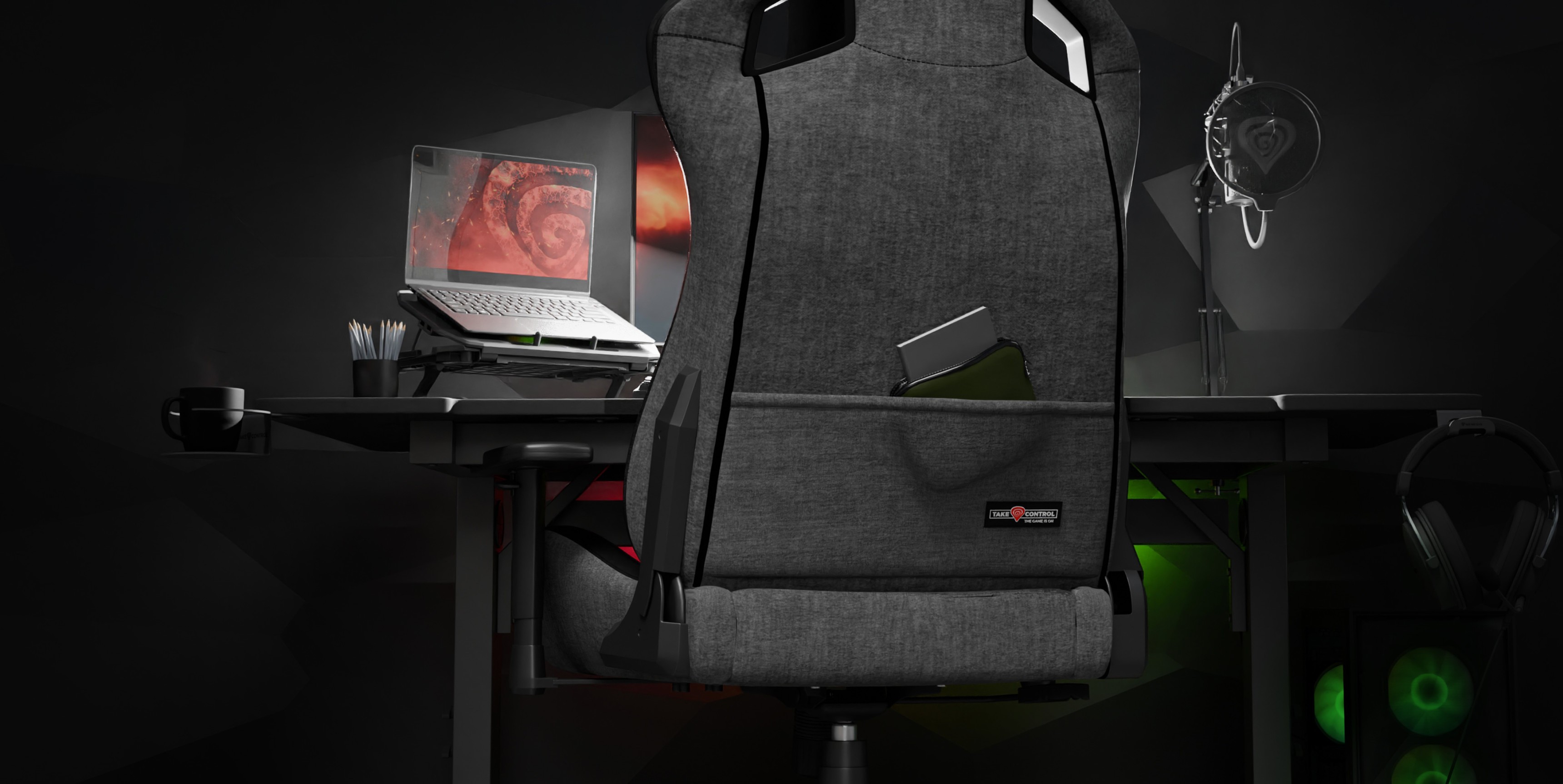 Chaise de jeu Genesis Nitro 660 grise positionnée derrière un bureau avec un ordinateur portable et des accessoires de jeu dans une pièce faiblement éclairée.
