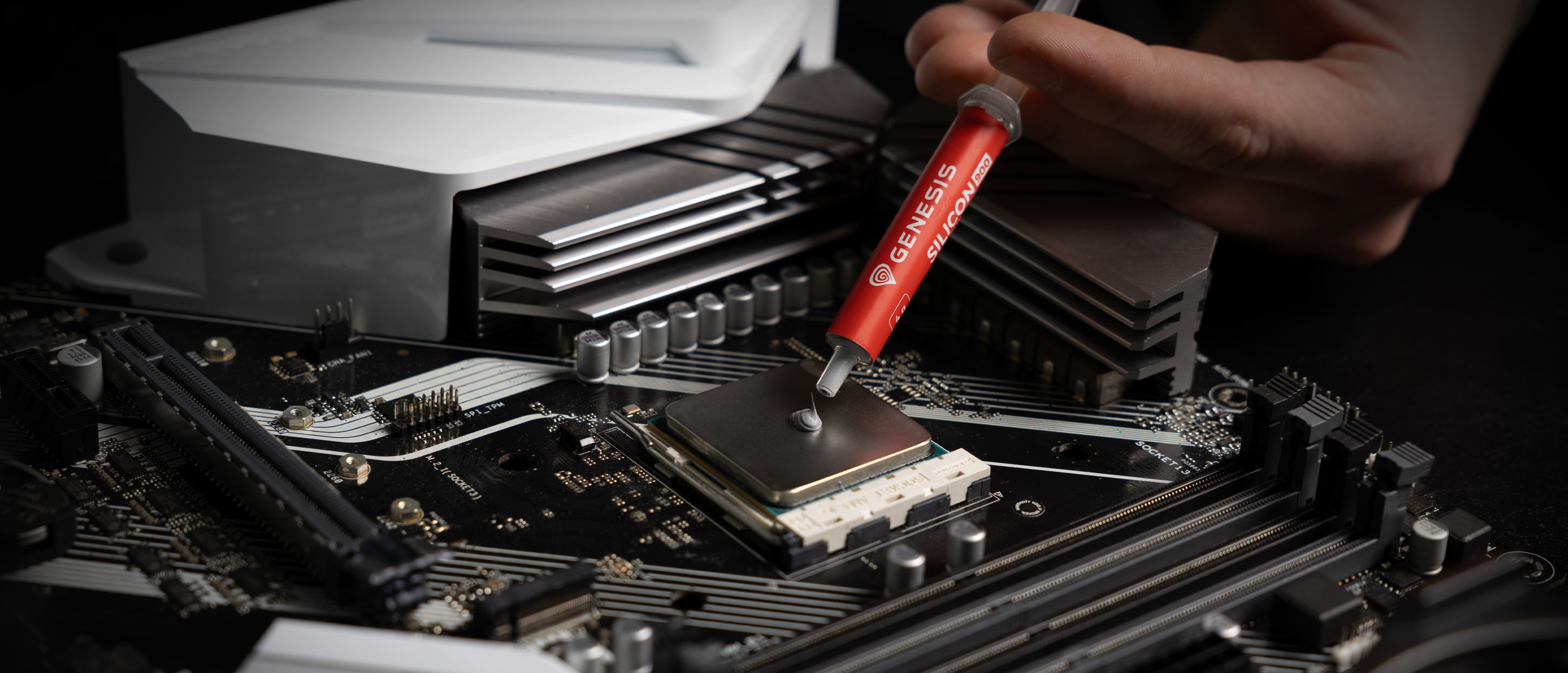 Application de la pâte thermique Genesis Silicon 900 sur le socle d'un processeur d'une carte mère pour améliorer la conductivité thermique.
