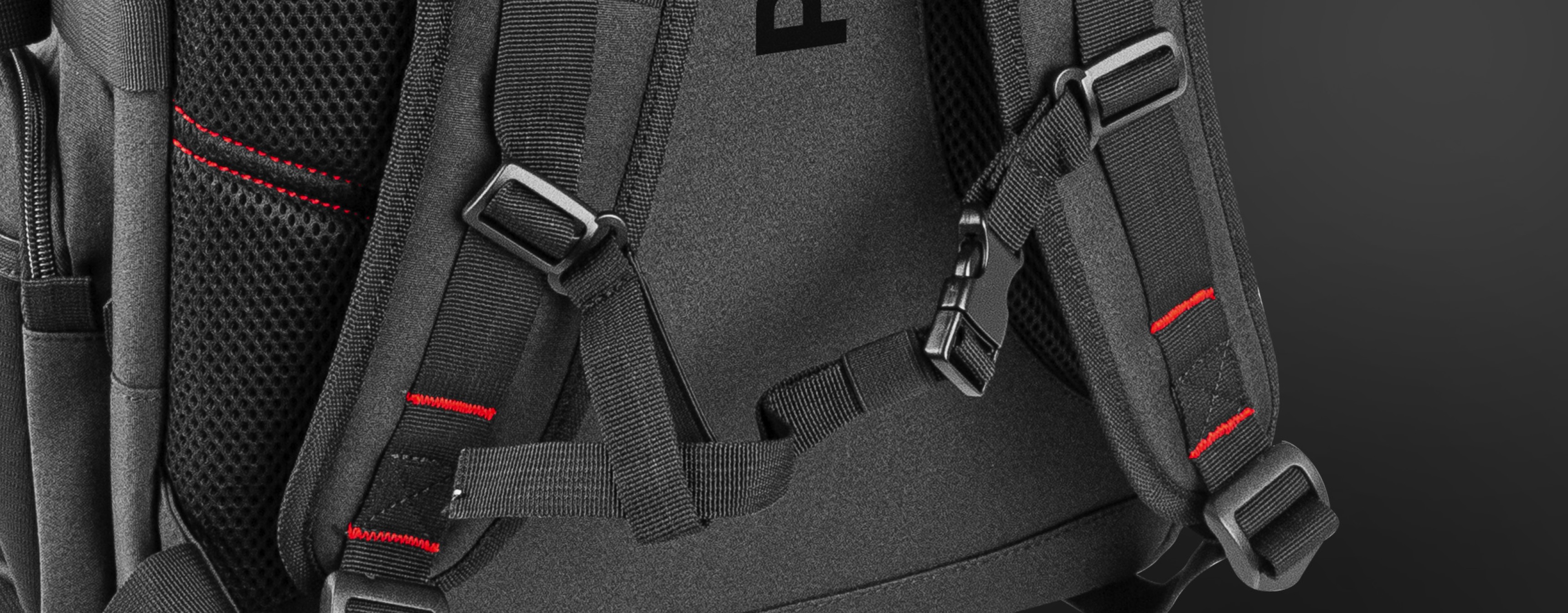 Gros plan sur le sac à dos pour ordinateur portable Genesis Pallad 550 qui comporte des bretelles réglables et des détails réfléchissants sur une surface noire.