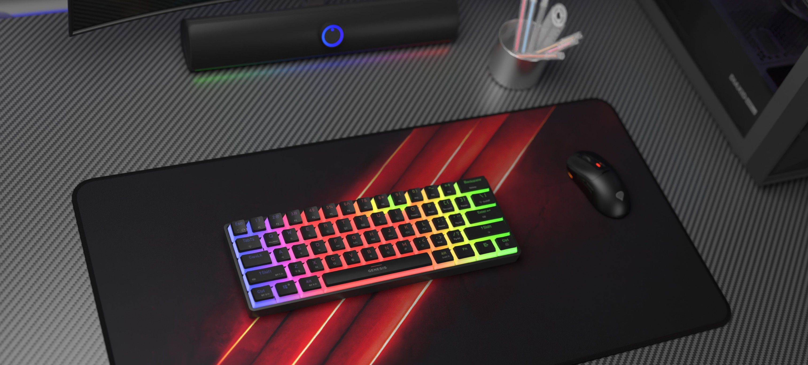 Clavier de jeu mécanique sans fil avec éclairage RVB, posé sur un tapis de souris de jeu noir aux côtés d'une souris de jeu et d'accessoires de bureau.