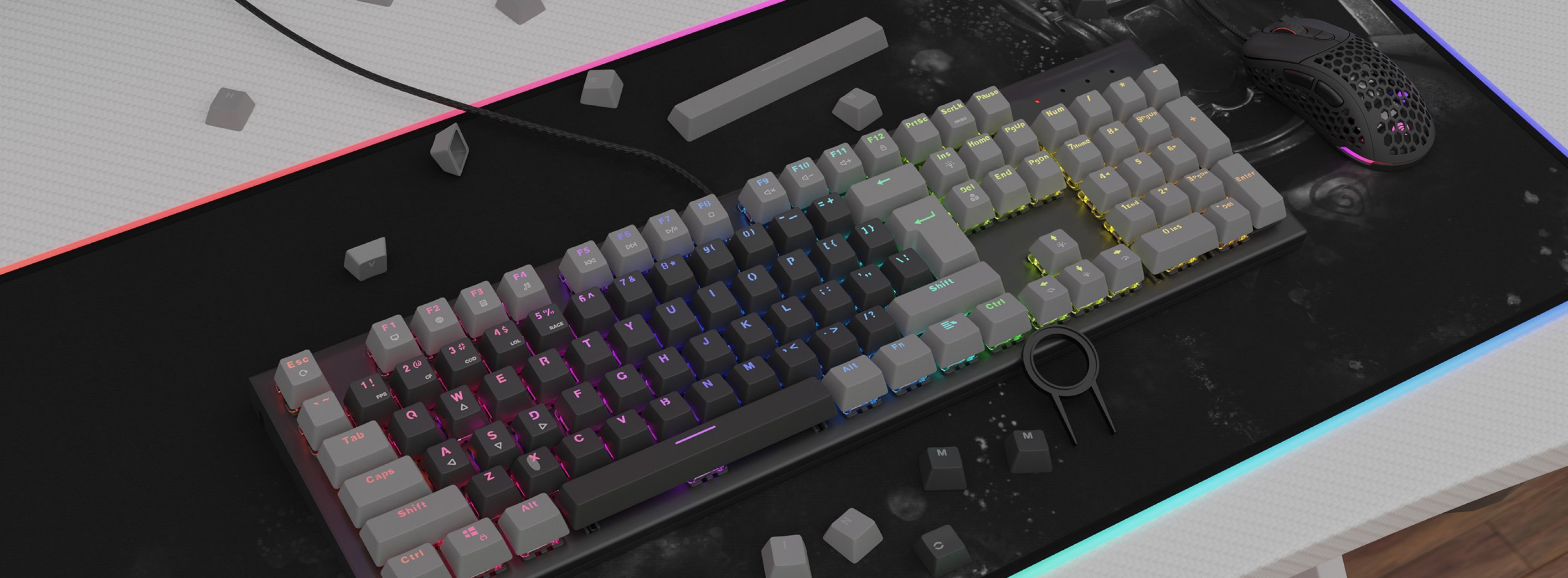 Un clavier mécanique avec un éclairage RVB coloré et des keycaps gris à double frappe, posés sur un tapis de souris texturé.