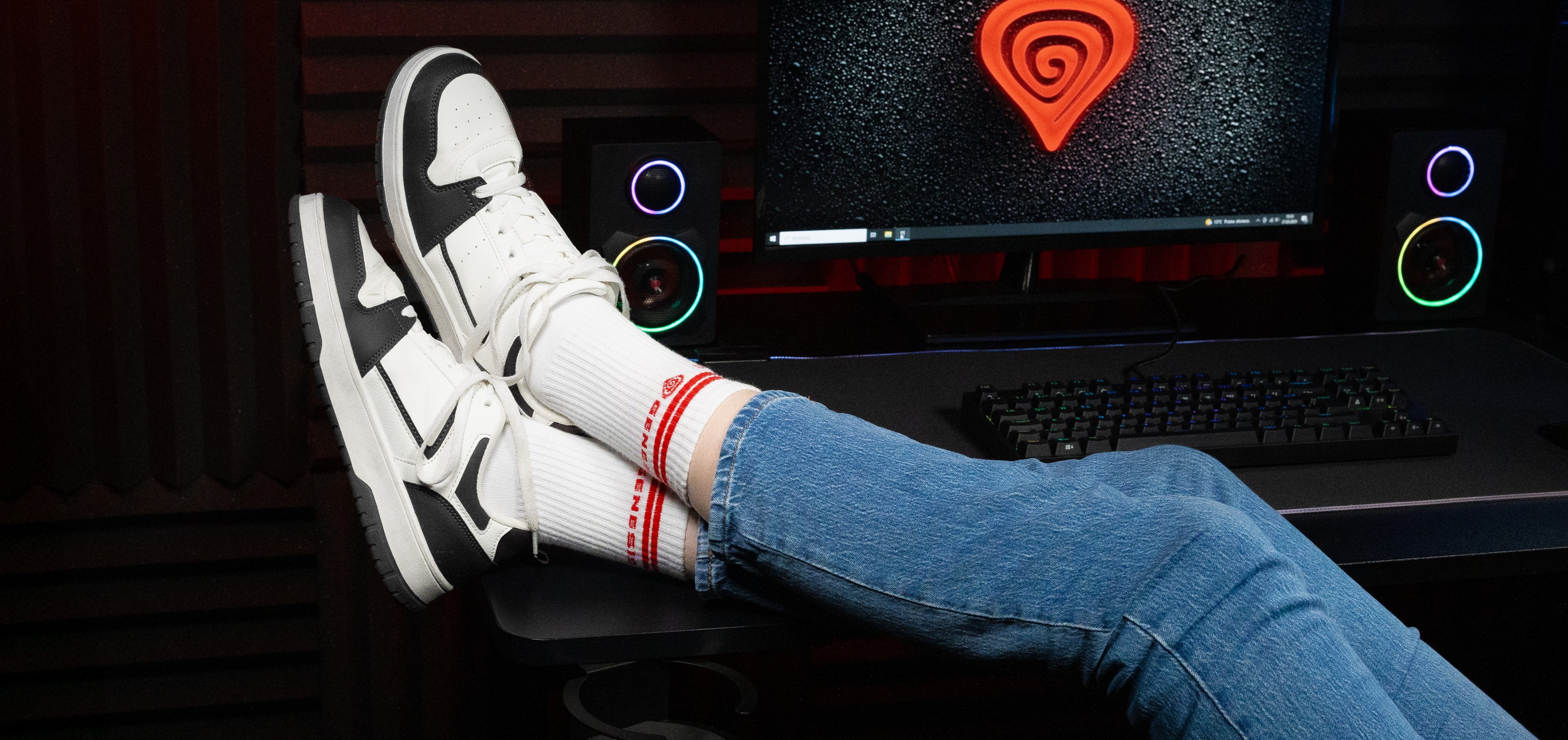 Chaussettes de sport blanches à rayures rouges, portées avec des baskets élégantes, et un jean bleu sur fond d'ordinateur.
